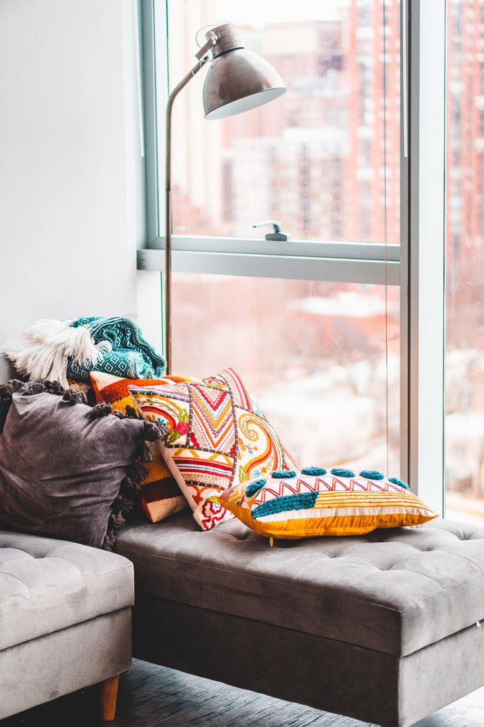 Chic interior space with vibrant cushions, a stylish lamp, and a large window view